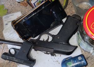 Zdjęcie przedstawiające zabezpieczone dwie sztuki broni oraz trzy telefony.