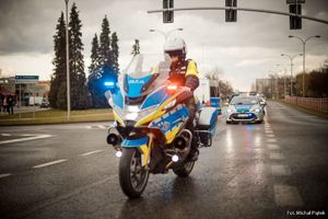 Zdjęcie przedstawiające uczestników rozpoczęcia sezonu oraz policjanta na motocyklu służbowym.