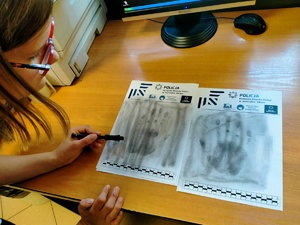 Zdjęcie przedstawiające Amelkę w trakcie odbijania odcisku dłoni na kartce papieru.