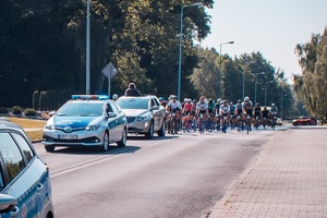 Zdjęcie przedstawiające radiowozy policyjne oraz rowerzystów.