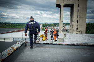 Zdjęcie przedstawiające Policjanta oraz Strażaków na dachu.