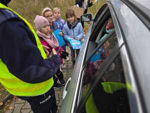 Zdjęcie policjanta oraz dzieci w trakcie kontroli drogowej.