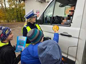 Zdjęcie policjantki oraz dzieci w trakcie kontroli drogowej.