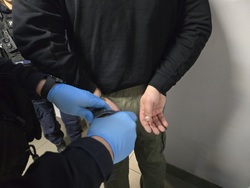 Zdjęcie przedstawiające moment zakładania kajdanek osobie zatrzymanej.