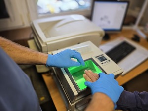 Zdjęcie przedstawiające moment pobierania odcisków linii papilarnych osobie zatrzymanej.