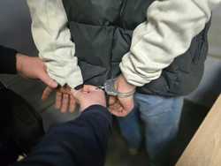 Zdjęcie policjanta zakładającego kajdanki zatrzymanemu.