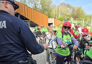 Policjant wręczający odblaski uczestnikom rajdu.
