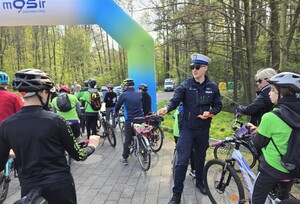 Policjant wręczający odblaski uczestnikom rajdu.