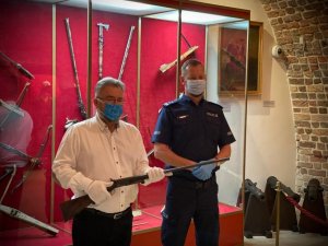 Policjant przekazuje broń dyrektorowi muzeum