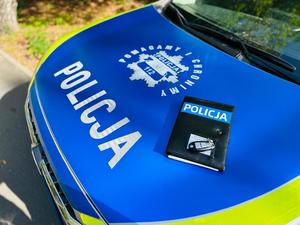 na zdjęciu maska oznakowanego radiowozu policji, na której leży karta od pojazdu i kluczyki
