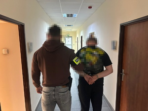 na zdjęciu nieumundurowany policjant trzyma zatrzymanego mężczyznę