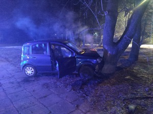 na zdjęciu pojazd, który po zderzeniu z drzewem. Z pojazdu wydobywa się dym.