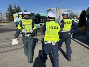 na zdjęciu dwóch policjantów i funckonariusz transportu drogowego idą w stronę autobusu miejskiego