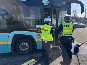 na zdjęciu dwóch policjantów stoi przy autobusie miejskim