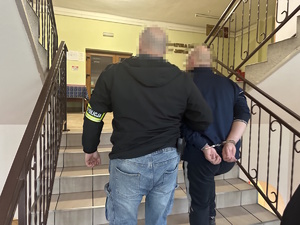 na zdjęciu nieumundurowany policjant prowadzi zatrzymanego mężczyznę w budynku prokuratury