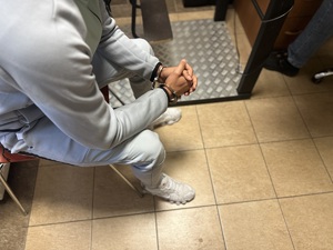 na zdjęciu widać ręce w kajdankach zatrzymanego mężczyzny