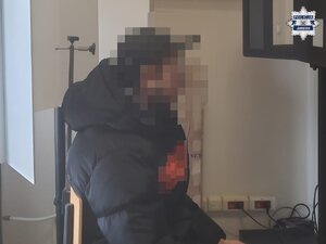 na zdjęciu zatrzymany mężczyzna w trakcie wykonywania zdjęcia sygnalitycznego u technika kryminalistyki