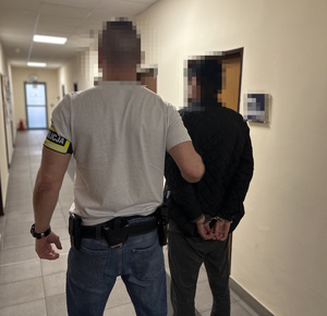 na zdjęciu nieumundurowany policjant trzyma zatrzymanego mężczyznę