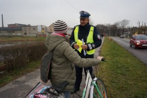 Policjant wręcza kamizelkę odblaskową.