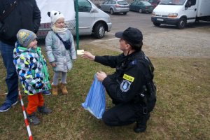 Policjant wręcza dzieciom odblaski.