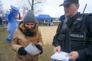 Policjant wręcza ulotki o bezpieczeństwie nad wodą.