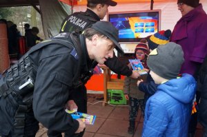 Policjant wręcza dzieciom odblaski.