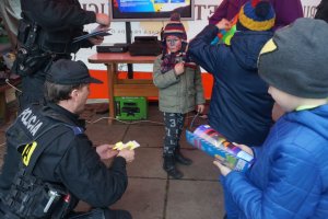 Policjant wręcza dzieciom odblaski.