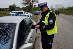 policjant kontroluje srebrny samochód