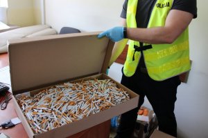 policjant kryminalny otwiera karton z papierosami luzem