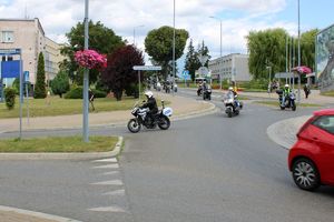 policyjny motocykl pilotuje kolumnę motocykli na rondzie
