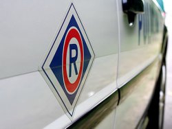 Zdjęcie przedstawia symbol ruchu drogowego-literę R na drzwiach radiowozu.