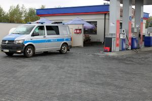 Zdjęcie przedstawia policyjny radiowóz oraz stację paliw.