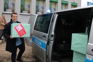 Zdjęcie przedstawia wolontariusza pakującego paczki do radiowozu.