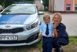Zdjęcie przedstawia policjantkę, dziewczynkę oraz radiowóz.