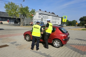 Zdjęcie przedstawia policjantów przeprowadzających kontrolę drogową.