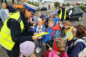 Zdjęcie przedstawia policjantkę, która rozdaje dzieciom odblaski.