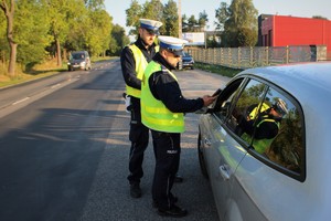 Zdjęcie przedstawia dwóch policjantów ruchu drogowego prowadzących kontrolę trzeźwości.