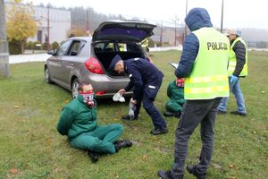 Zdjęcie przedstawia policjantów w kamizelkach oraz zatrzymanego.