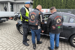 Zdjęcie przedstawia policjanta oraz motocyklistów przekazujących naklejkę kierowcy.