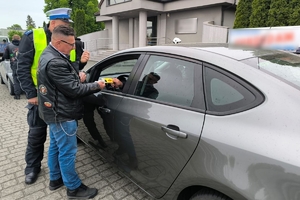 Zdjęcie przedstawia policjanta oraz motocyklistę przekazujących naklejkę kierowcy.