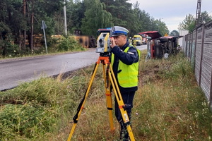 policjant wykonuje oględziny na miejscu zdarzenia drogowego - wykonuje pomiary