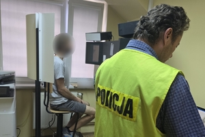 Zdjęcie przedstawia policjanta w kamizelce odblaskowej oraz mężczyznę w kabinie podczas zdjęcia.