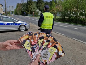 na zdjęciu widoczne są ulotki promujące trzeźwość za kierownicą, jak również umundurowany policjant i oznakowany radiowóz