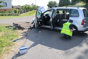 na zdjęciu widoczny  jest uszkodzony samochód obok niego policjant opisuje uszkodzenia