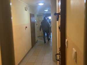 na zdjęciu widoczne jest pomieszczenie dla osób zatrzymanych policjant w cywilnym ubraniu z opaska na ręce z napisem policja
