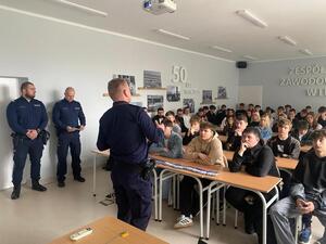 funkcjonariusz Straży Ochrony Kolei policjant stoją przed uczniami siedzącymi w sali lekcyjnej