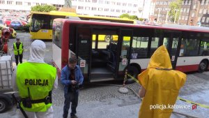 Policjant odprowadza kobietę do autobusu