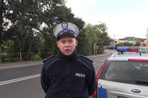 Policjant na tle radiowozu