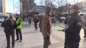 Policjanci wraz z księdzem wręczają pieszym elementy odblasko