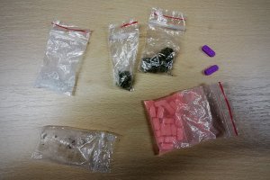 Na kolorowym zdjeciu widać pięć opakowań z narkotykami, które leżą na stole oraz dwie tabletki.